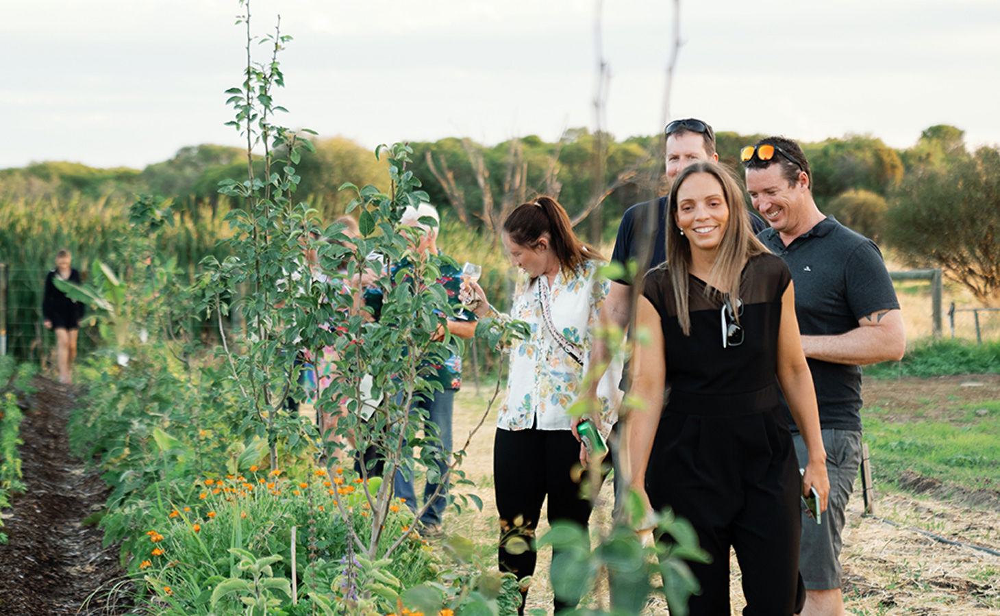 People exploring 11 Acre Farm walking next to the vegetable garden