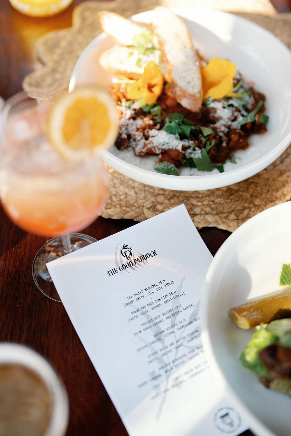 The Good Paddock branded menu amongst food and drinks on a table