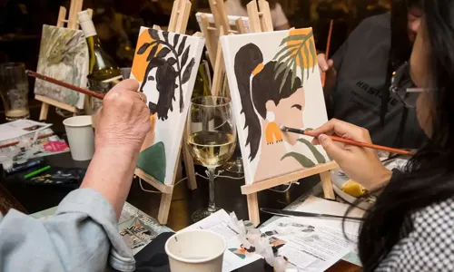 2 ladies painting with a glass of bubbly