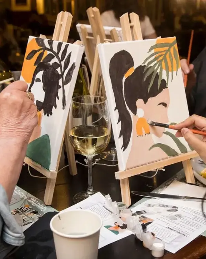 2 ladies painting with a glass of bubbly