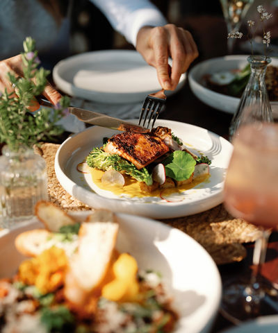 A person cutting into a meal with a knife and fork
